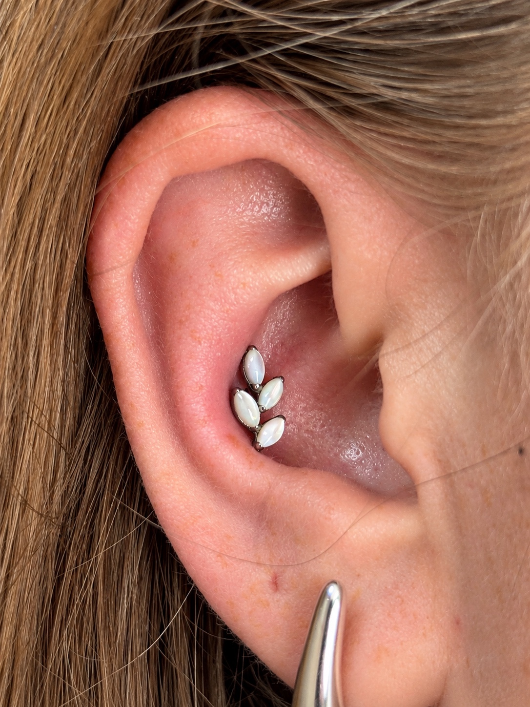 Piercing con joyería de ópalo realizado por MYO Piercing